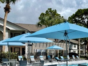 a swimming pool with tables and chairs under umbrellas