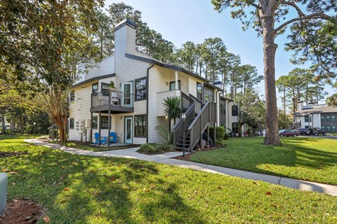 A two-story house with a balcony and a tree in front.