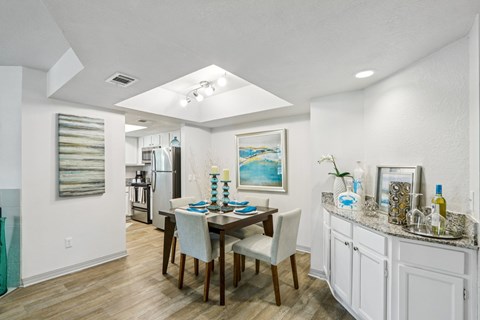 A dining room with a table set for two and a painting on the wall.
