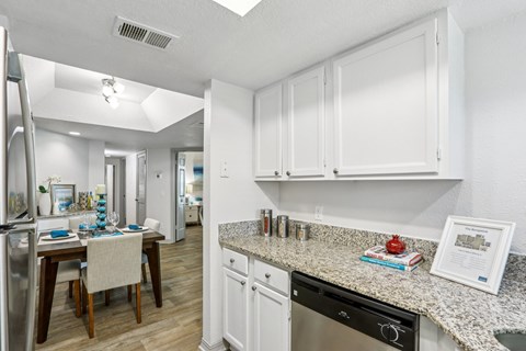A kitchen with white cabinets and a granite countertop.