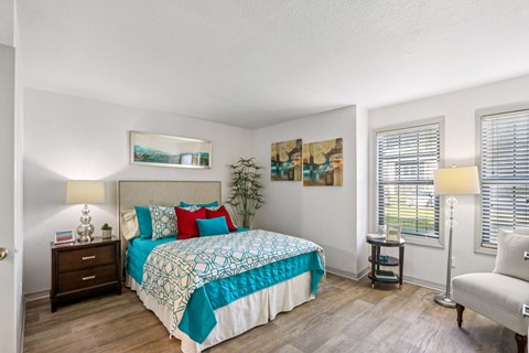 A bedroom with a bed, nightstand, chair, and two lamps.