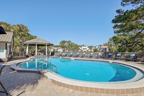 A small pool with a tiled edge and a gazebo in the background.