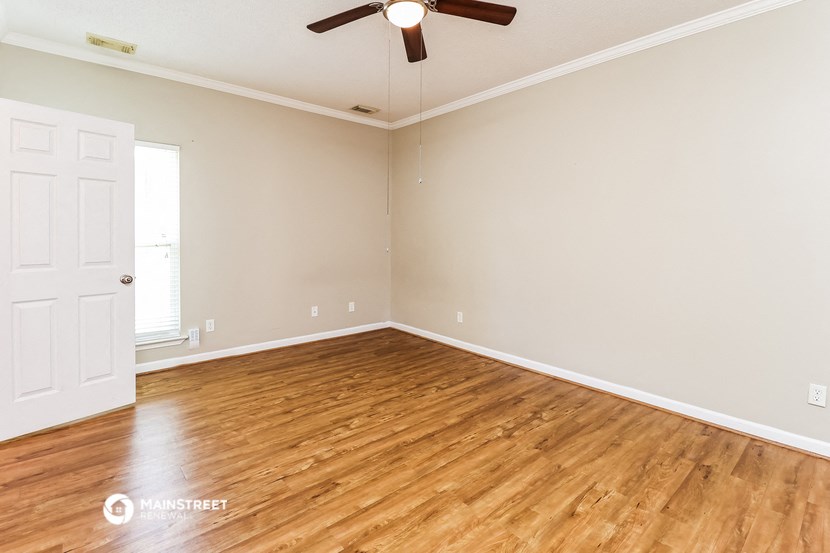 an empty living room with wood floors and a ceiling fan