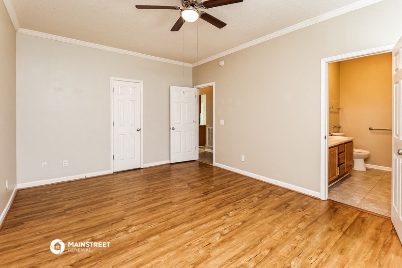 an empty living room with wood flooring and a ceiling fan