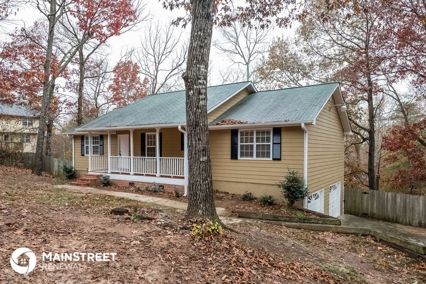 a small yellow house with a tree in front of it