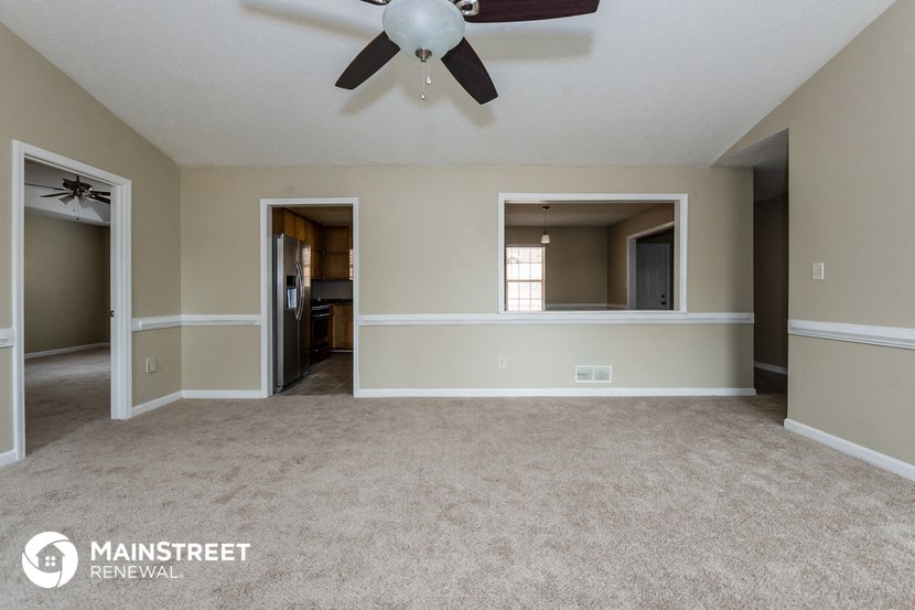 an empty living room with a ceiling fan