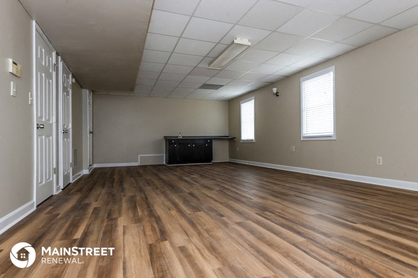 the spacious living room with wood flooring and white walls