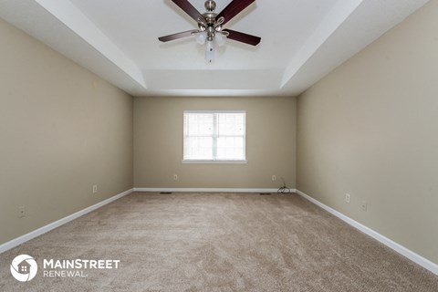 the spacious living room with ceiling fan and carpet