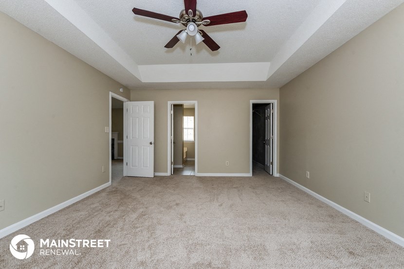 a living room with carpet and a ceiling fan