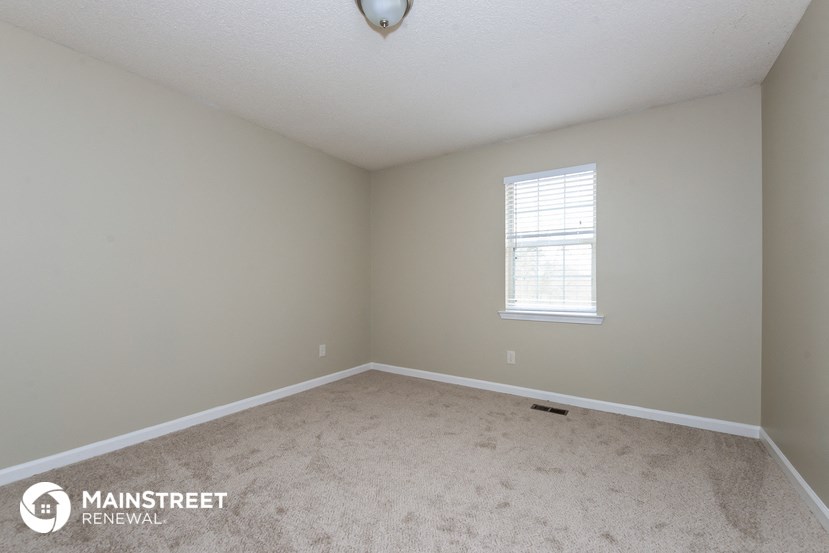 the spacious bedroom with carpeting and a window