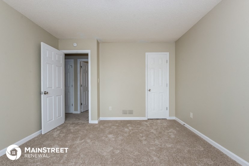 a bedroom with two doors and a carpeted floor