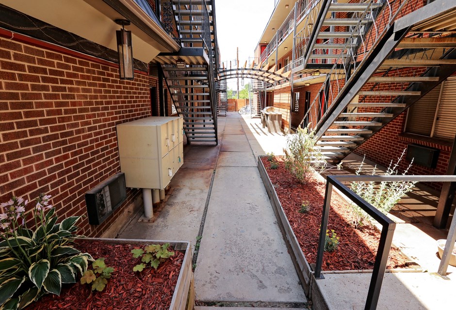 a corridor between two buildings with stairs and plants
