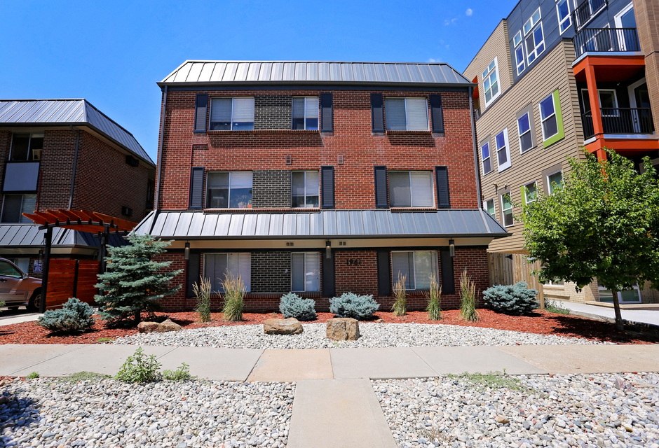 an exterior view of a brick apartment building with a sidewalk and landscaping