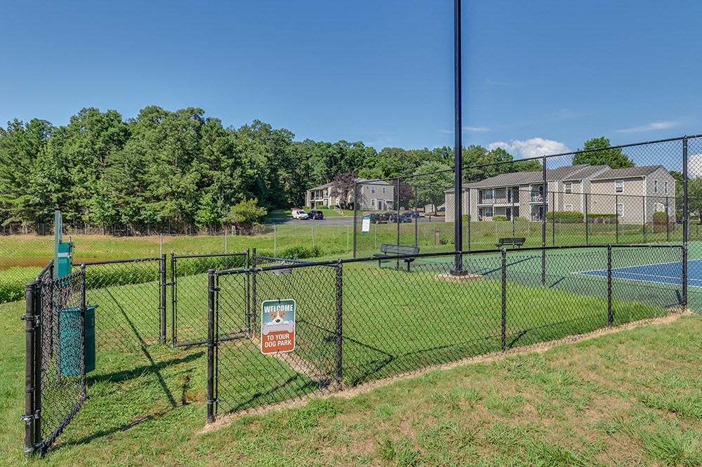 a tennis court in a fenced in area with houses in the background