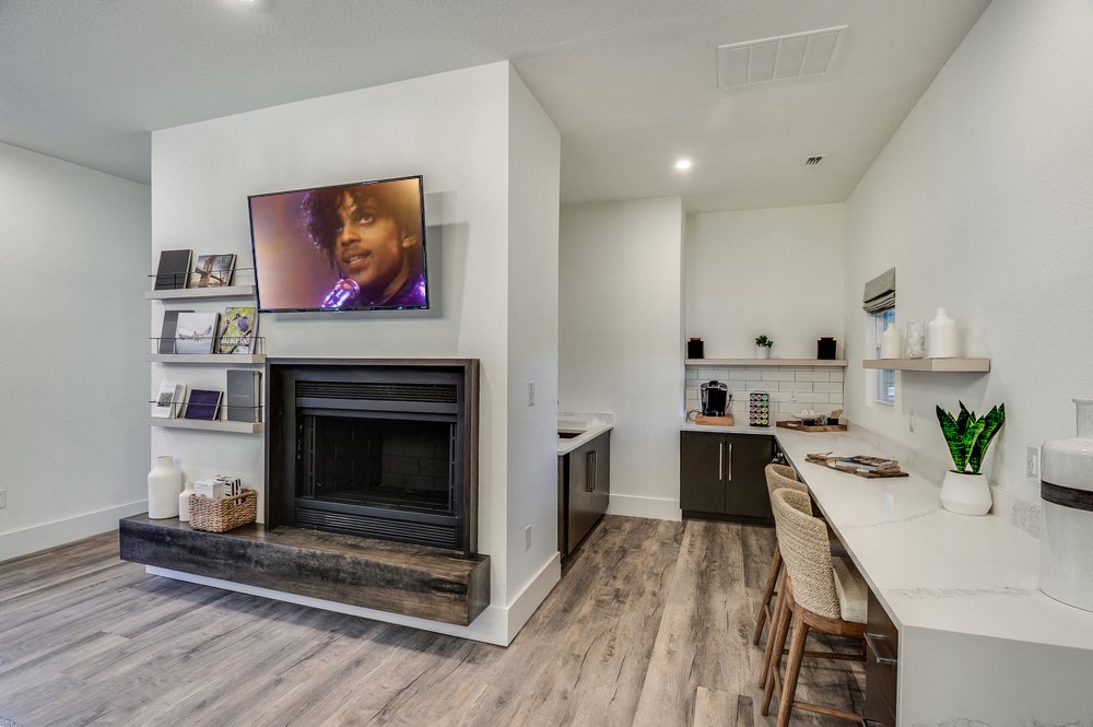 a living room with a fireplace and a kitchen with a table and chairs