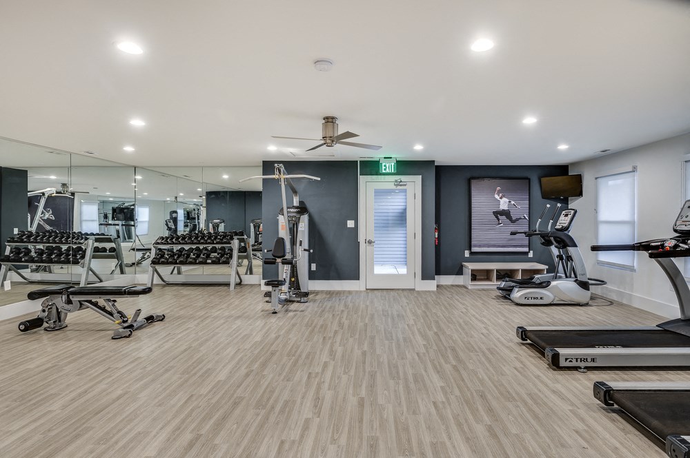 a gym with weights and cardio machines and a ceiling fan