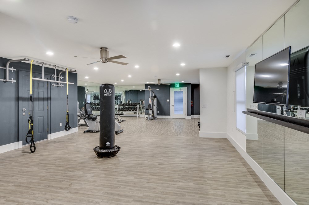 a gym with a weights rack and a tv on the wall
