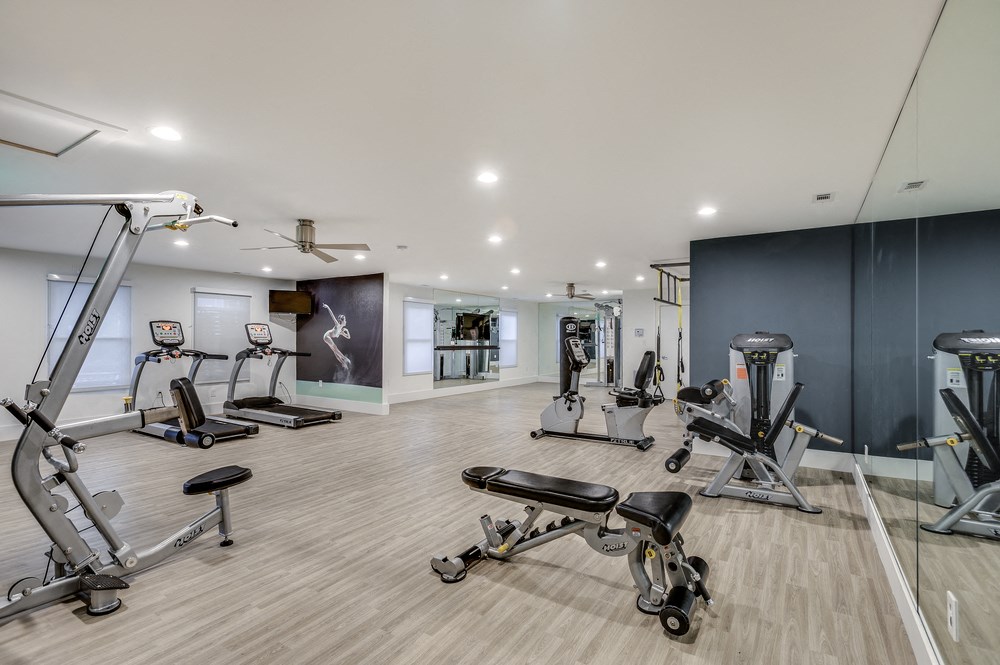 a gym with treadmills and other exercise equipment on a wood floor
