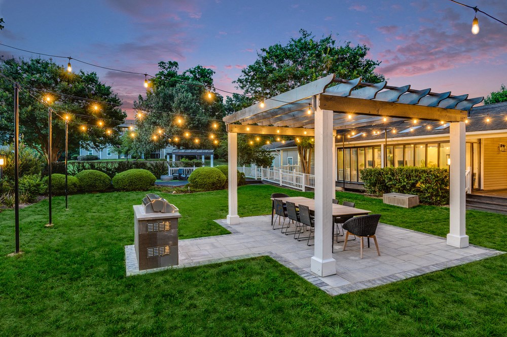 a backyard patio with a table and a pavilion with lights