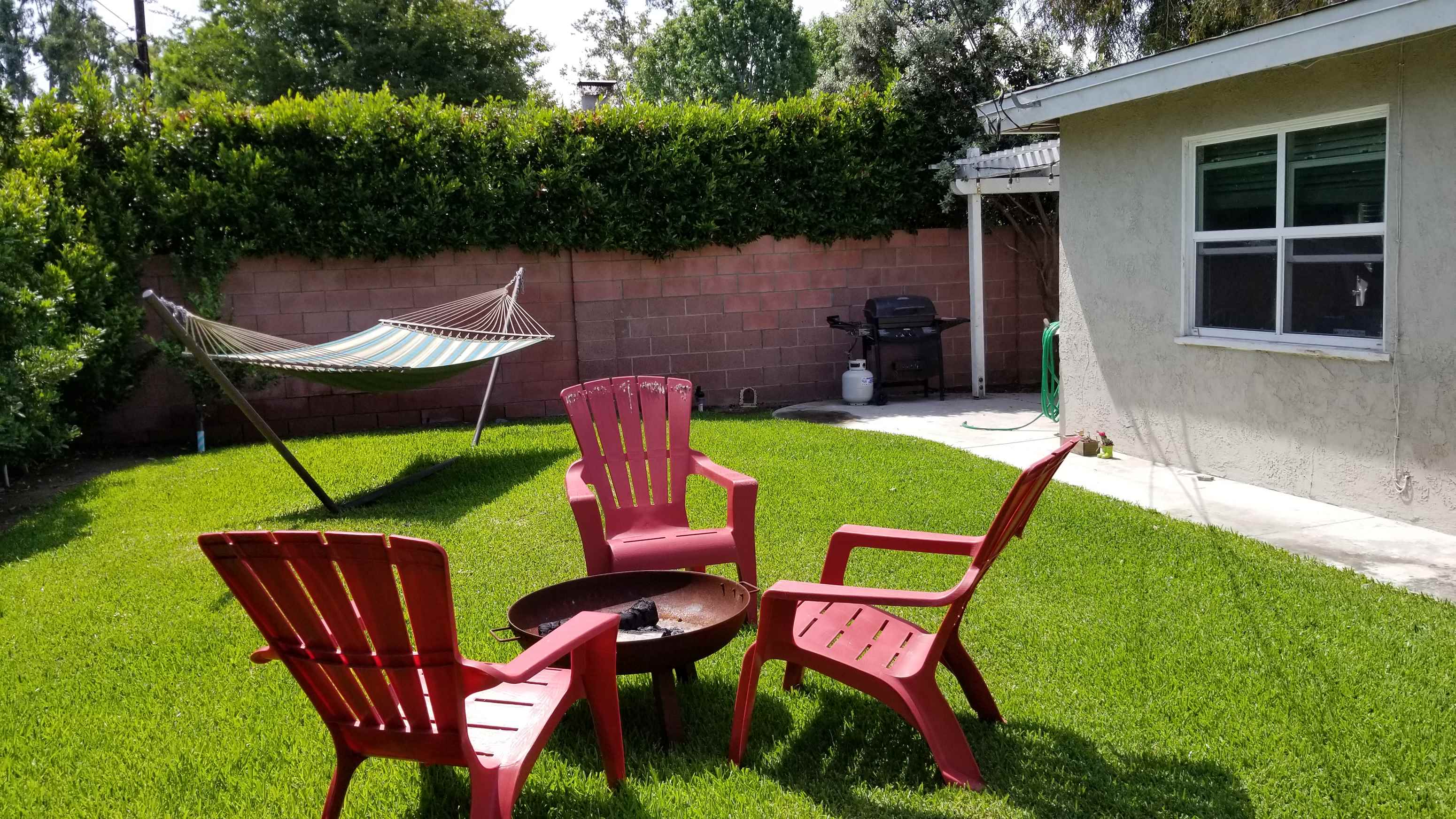a backyard with chairs and a table and a hammock
