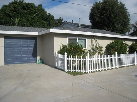 a white picket fence in front of a house with a blue garage door