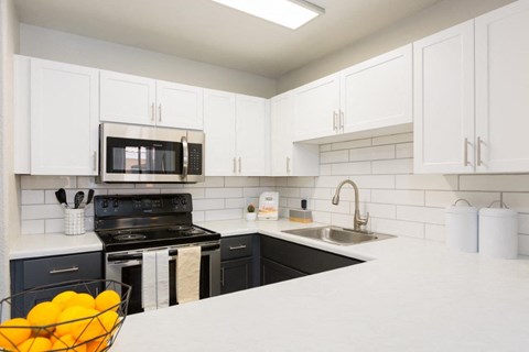 A kitchen with white cabinets and a black stove top oven.