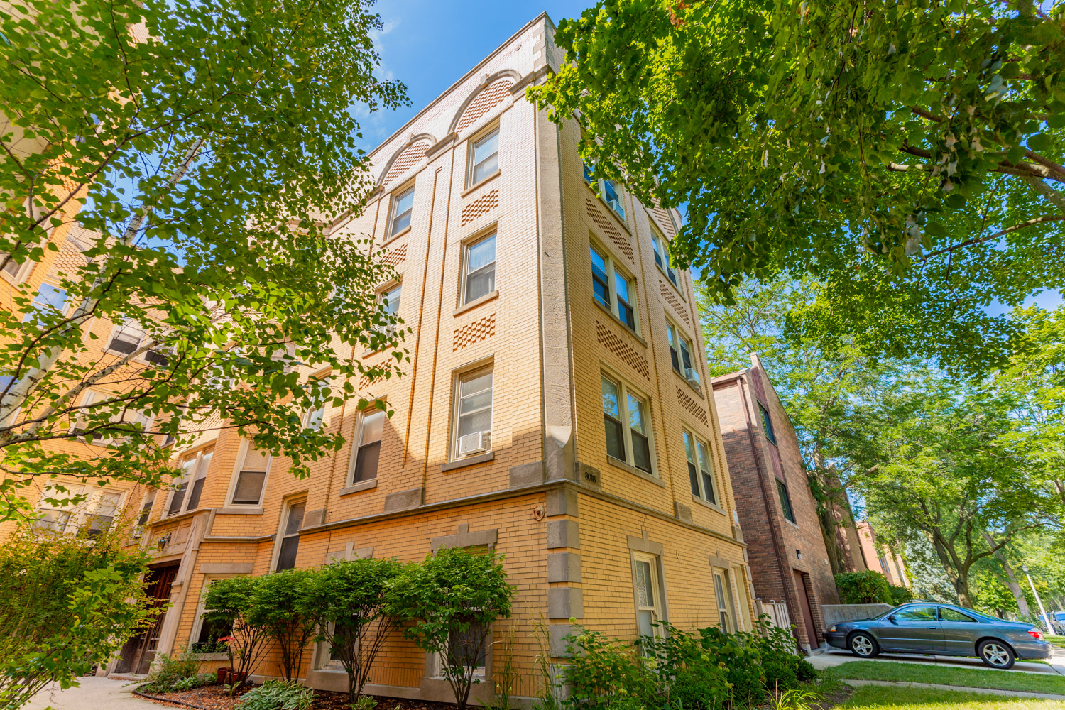 a tall building with a green car parked in front of it