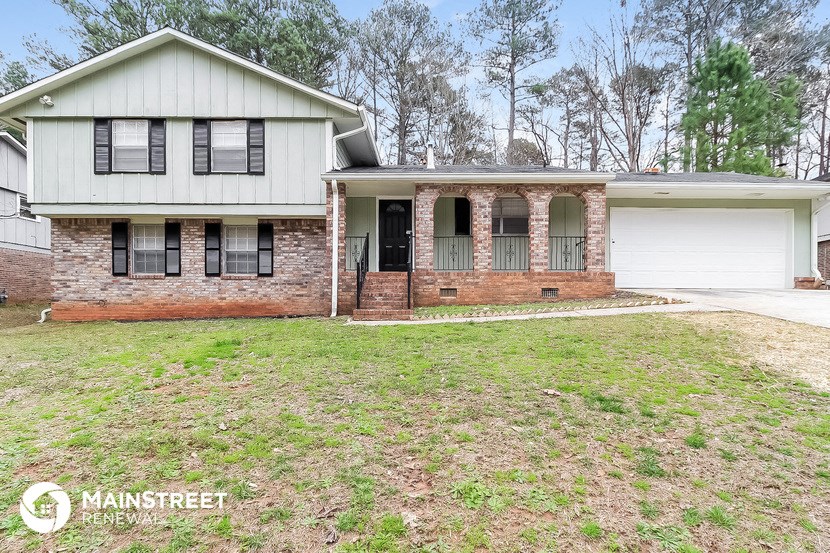 a brick house with black shutters and a white garage