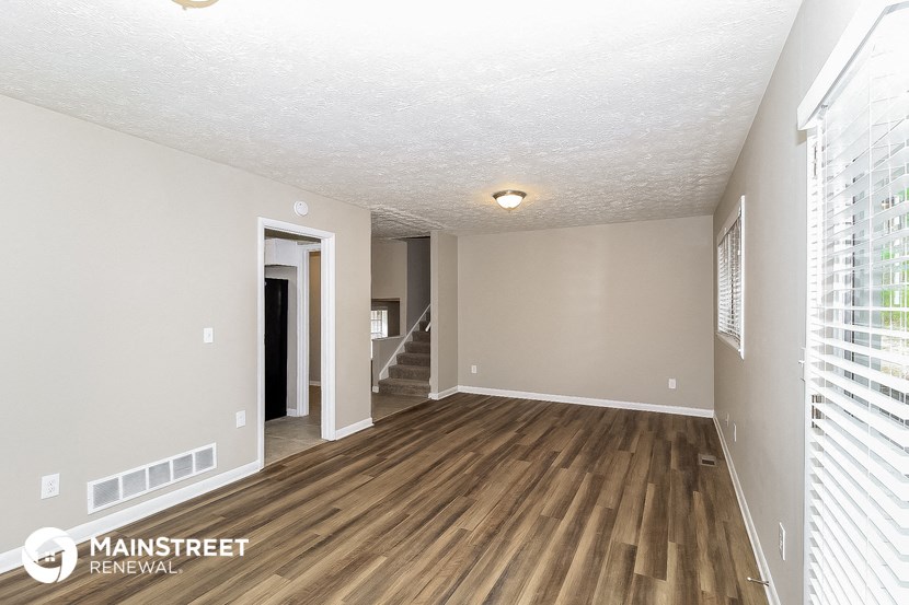 the living room and dining room of an apartment with wood flooring