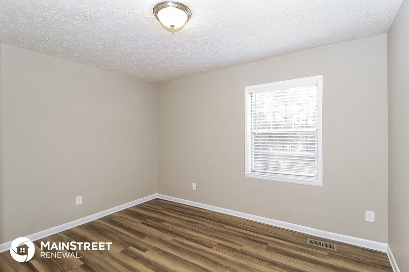 the interior of an empty room with wood flooring and a window