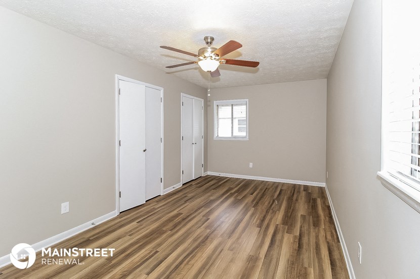 the living room of an apartment with wood flooring and a ceiling fan