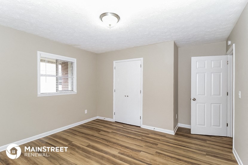 the living room of an apartment with wood floors and a white door