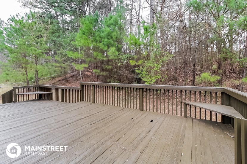 a deck with a bench and trees in the background