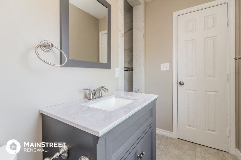 a bathroom with a sink and a mirror and a door