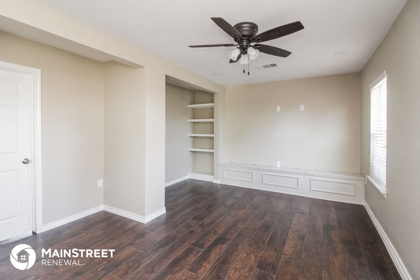 a living room with wood floors and a ceiling fan