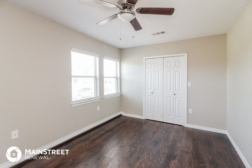 the spacious living room with wood flooring and a ceiling fan
