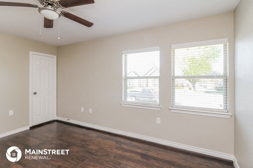 the interior of a room with wood flooring and a ceiling fan