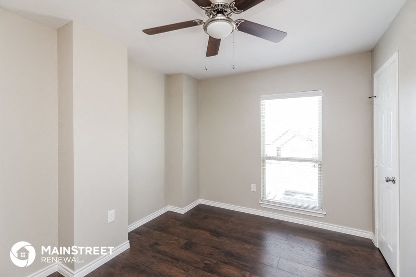 an empty room with a ceiling fan and a window