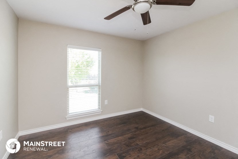 the spacious living room with wood flooring and a ceiling fan