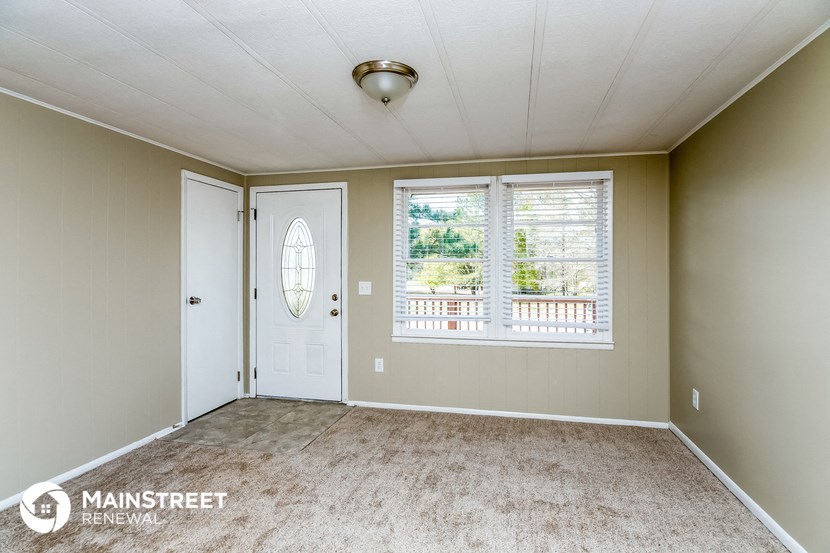 an empty living room with a white door and window