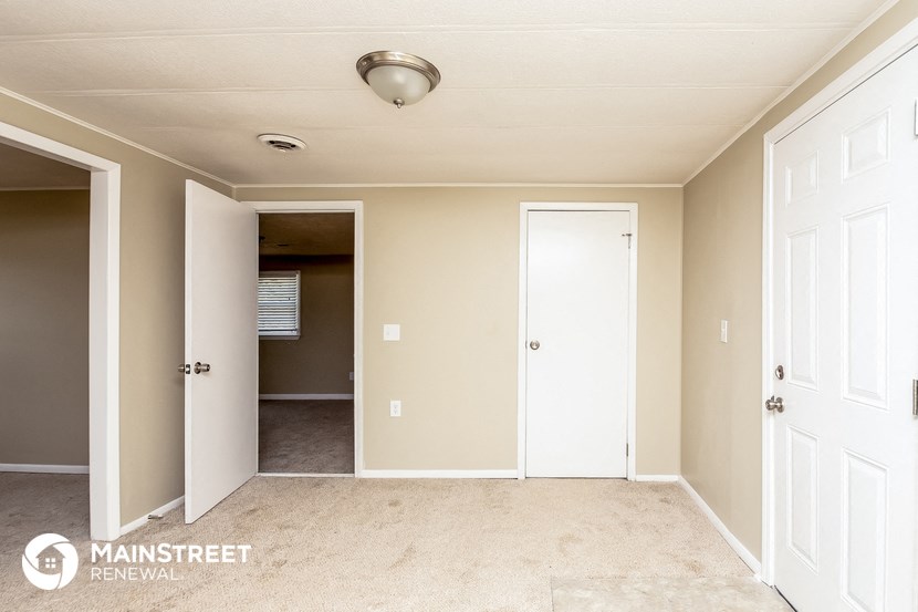a bedroom with two closets and two doors and a carpeted floor