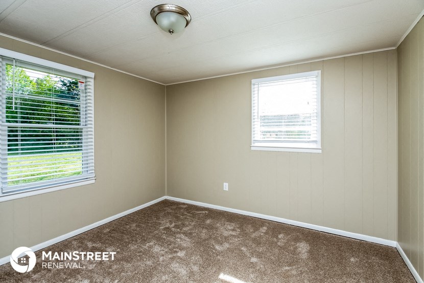 a room with a carpeted floor and two windows