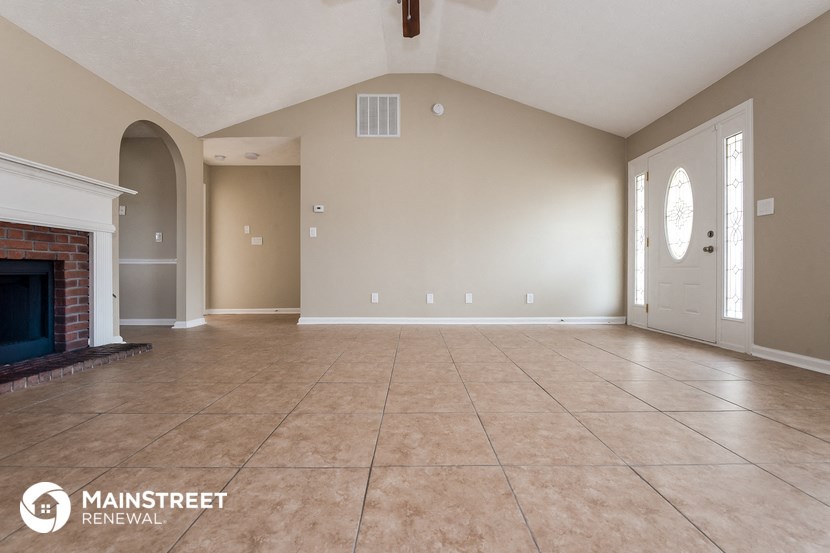 an empty living room with a fireplace and tile flooring