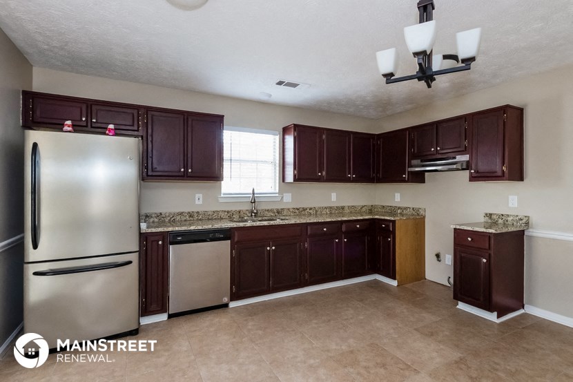 a kitchen with dark cabinets and a stainless steel refrigerator