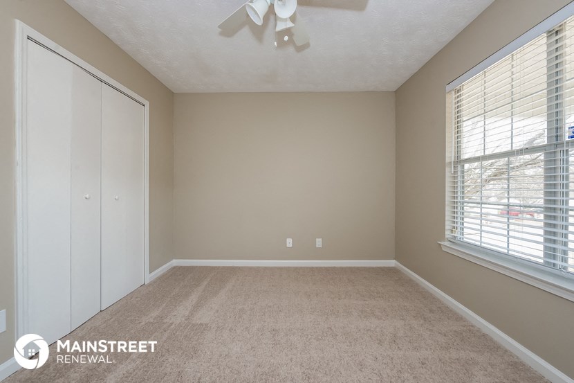 an empty living room with a closet and a large window
