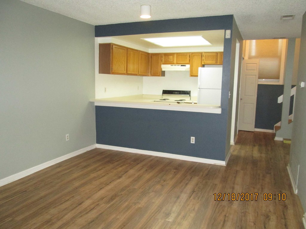 an empty kitchen with a blue wall and wooden floors