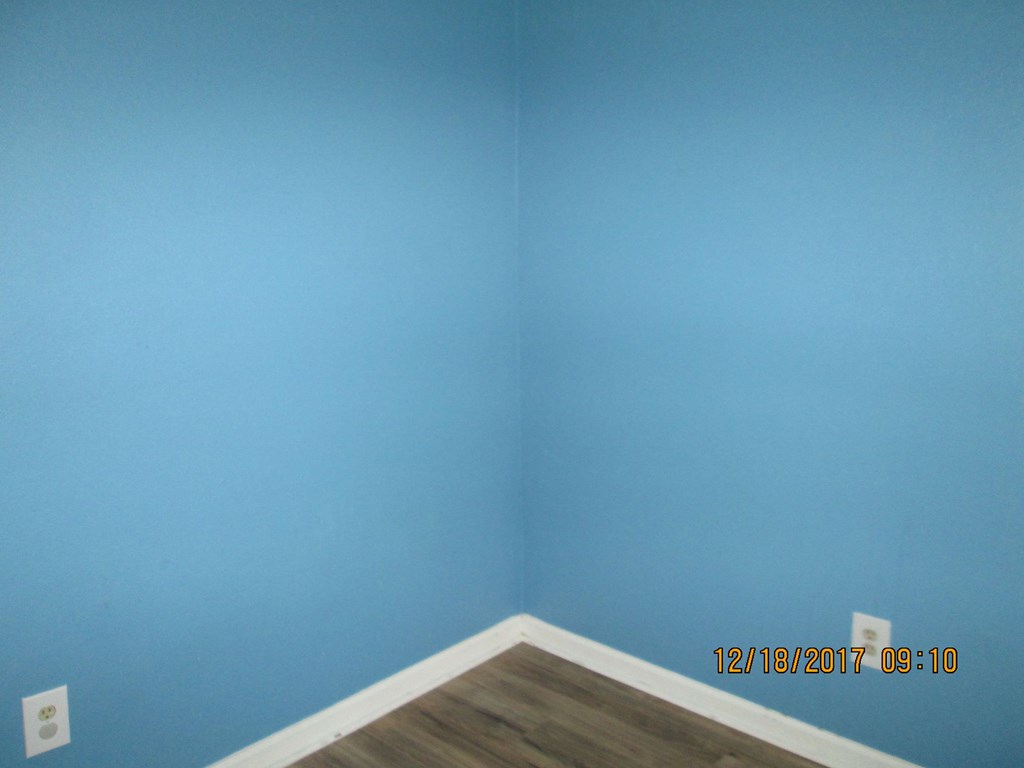 the corner of a room with blue walls and a wooden floor