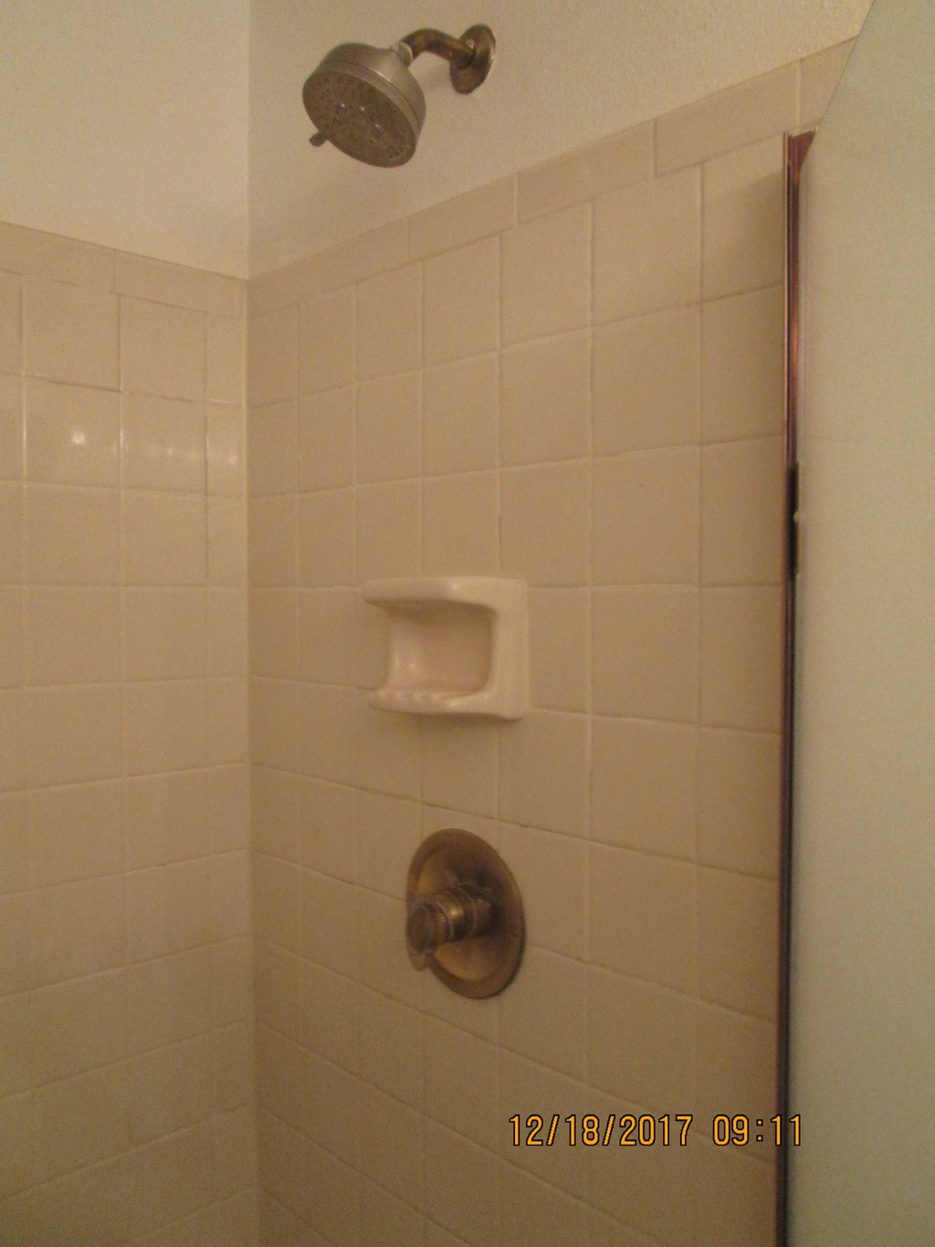 a white tiled shower in a bathroom with a soap dispenser