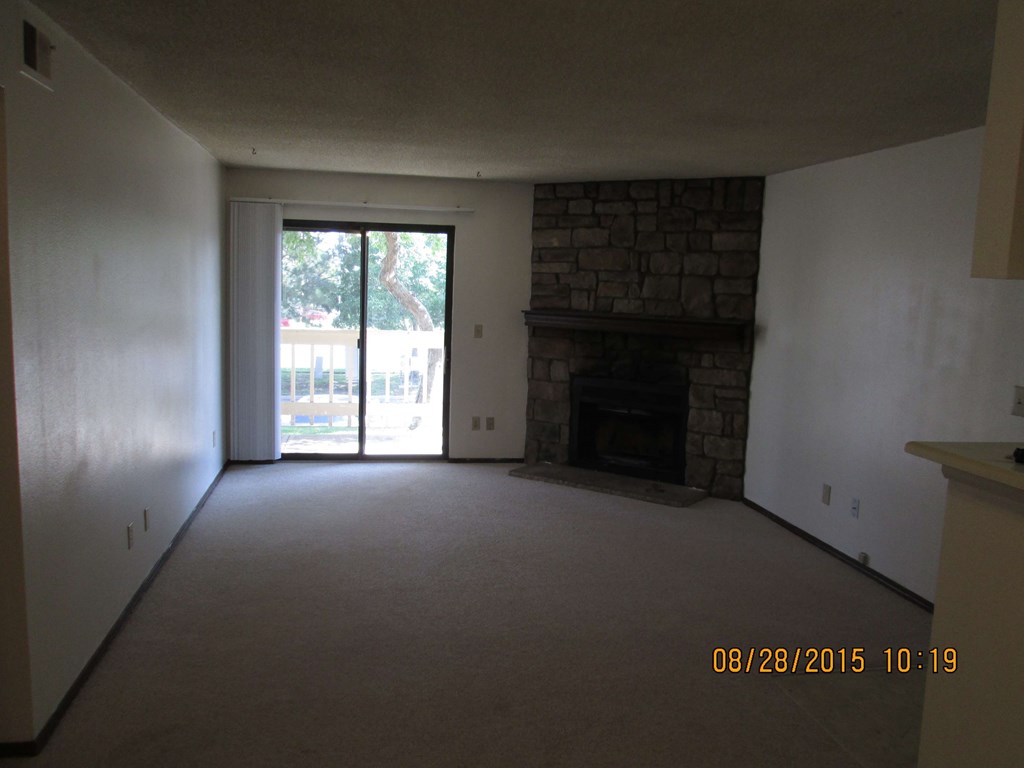 an empty living room with a fireplace and a sliding glass door