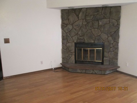 a living room with a stone fireplace and wooden floors